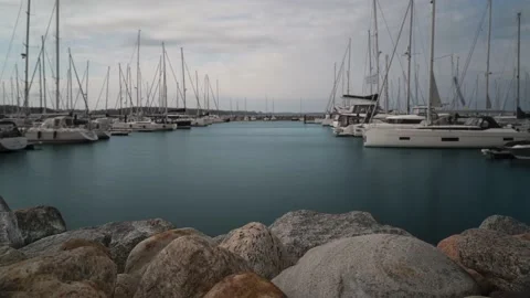 Focused rocks in foreground water movement with yachts of a harbor in background Stock Footage 196942764
