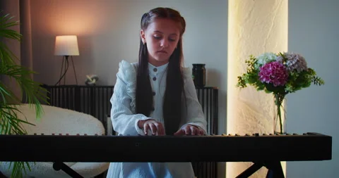 Focused school-age girl learning basic chords on electronic piano 스톡 동영상 314197743