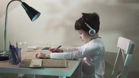 Focused School Child Studying at Table doing homework School Kid Drawing on Stock Footage 171788099