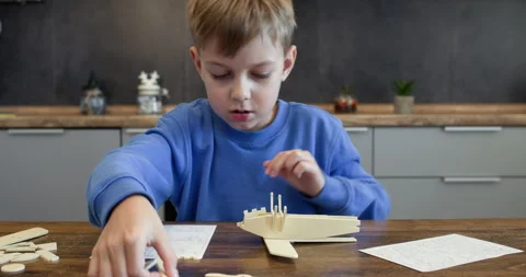 Focused schoolboy reads instruction guide assembling airplane Stock Footage 323973079