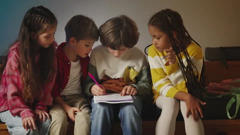 Focused schoolchildren solving math equations and writing in notebook together Stockbeeldmateriaal 335685150