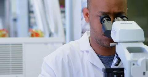 Focused scientist examines samples under a microscope in a lab Фото