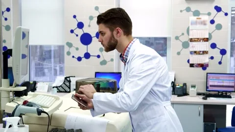 Focused scientist transferring data from computer to tablet in a modern lab Stock Footage 311826610