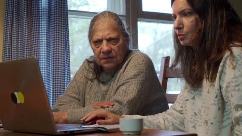 Focused Senior Adult Learns Computer Skills from Daughter at Kitchen Table Stock Footage 321154246
