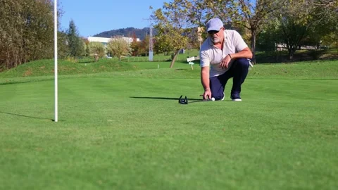 Focused senior golfer measuring with the putter on green for precise shot Stock Footage 292017295