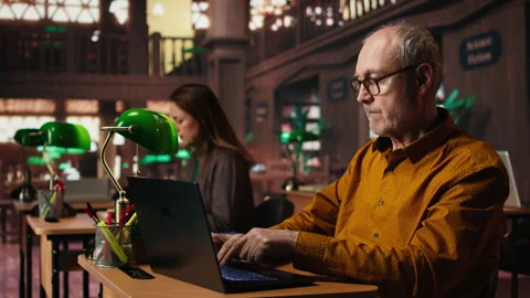 Focused senior guy reading academic text on laptop at the university Stock Footage 313310090