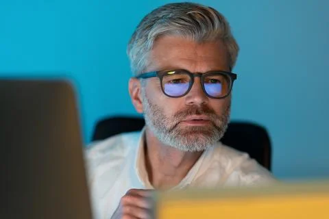 Focused Senior Man Working on Computer with Blue Light Glasses Stock-Fotos