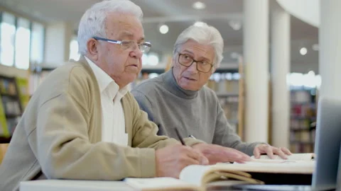 Focused senior men writing abstract in notebook in library Stock-Footage 232620861