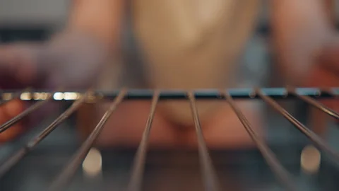 Focused shot of baker handling oven rack in cozy kitchen. Cinematic closeup of Stock Footage 337465694