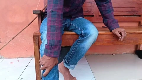 A focused shot of a young man sitting down, clutching his painful knee. Stock Footage 321939121