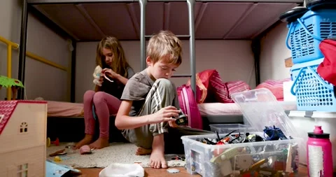 Focused siblings playing with doll and toys near bunk bed Stock Footage 294316286
