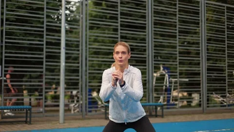 Focused slim lady in sportswear practicing wide squats during outdoors training Stock Footage 252194767