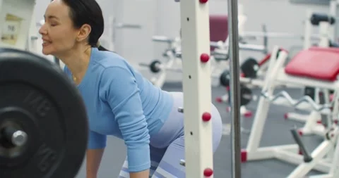 Focused Smith machine barbell curls build arm strength during a dynamic gym Stock Footage 325363025