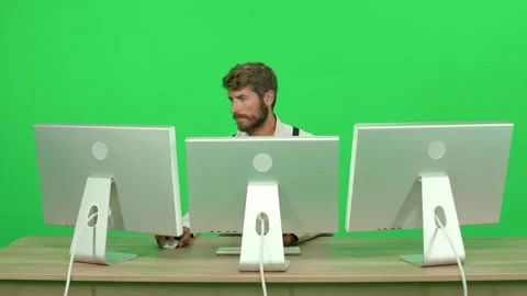 Focused software developer working on a PC while sitting at a desk, green Stock Footage 237221456