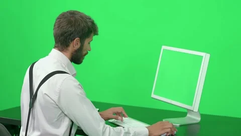 Focused software developer working on a PC while sitting at a desk, green Stock Footage 237249238