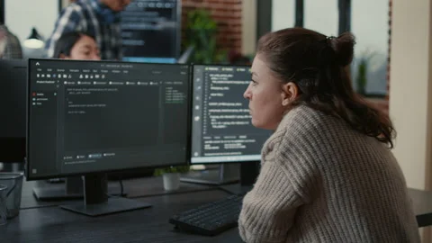 Focused software developer writing code looking at multiple computer screens Stock Footage 168232819