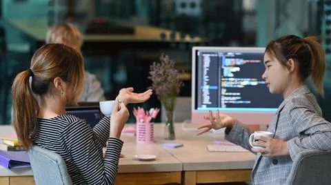 Focused software developers colleagues discussing and working on web site Foto stock