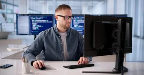 Focused Software Engineer Programming At Desk In Modern Office Foto stock