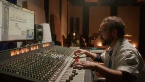 Focused Sound Engineer Working on Audio Tracks at Studio Mixing Desk Stock Footage 334364435