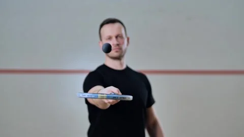 Focused squash player bounces ball above racket in sharp commercial frame Stock Footage 322149871