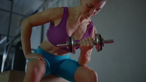 Focused Strength Training: A Woman's Determined Workout with Dumbbells in a Видео 329818686