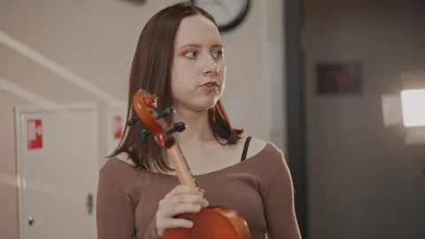 Focused student adjusts instrument before class begins. Preclass routine Stock Footage 346555447