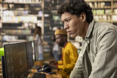 Focused student leaning toward computer monitor in library computer class Stock Photos