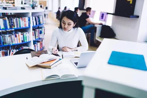 Focused student reading textbook in library Stock Photos