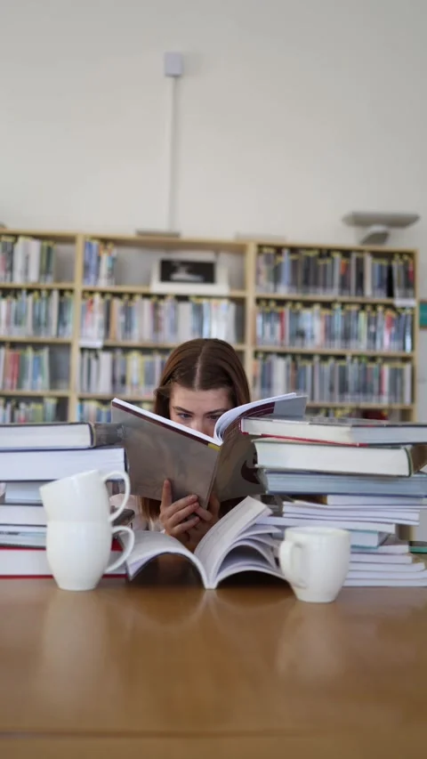 Focused student reads textbook closely while preparing for exams in library Stockbeeldmateriaal 342178554