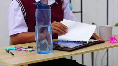 Focused Student in school uniform drinking from mug and organizing academic Stock Footage 335124254