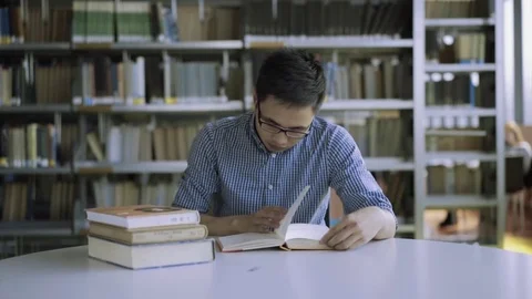 Focused student studying at desk in library in college Stock Footage 80532382