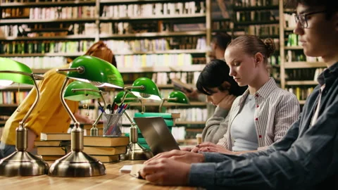 Focused student typing and taking notes on laptop for university assignment Stock Footage 336358721