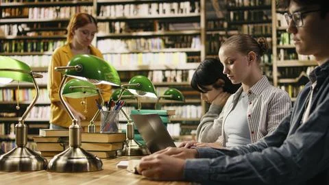 Focused student typing and taking notes on laptop for university assignment Stock Photos
