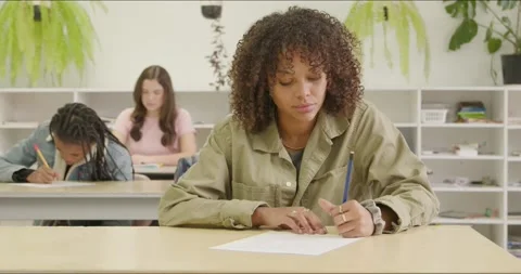 Focused Student Writes Final Exam Essay Test in Class. Tutoring Growth in Stock Footage 295633441