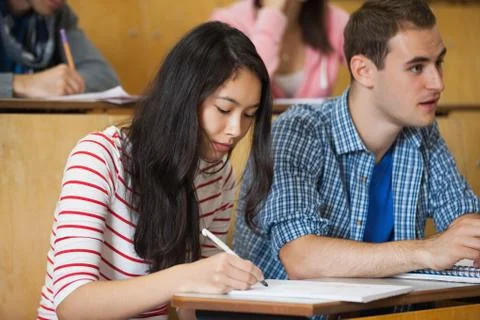 Focused students taking notes in lecture hall Photos