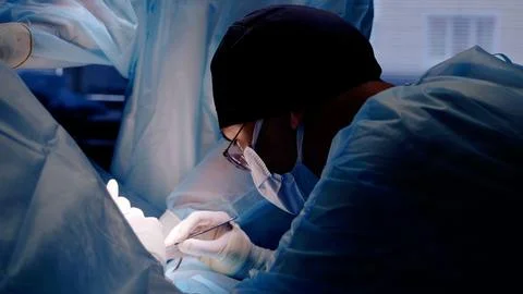 Focused surgeon performs a delicate operation in a sterile operating room Stock Photos