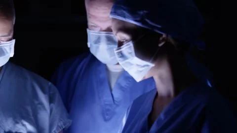 Focused Surgeons Performing Operation Under Surgical Light Stock Footage 314303393