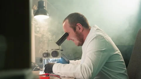 Focused Technician Soldering Circuit Board Under Microscope in Precision Stock Footage 286315645