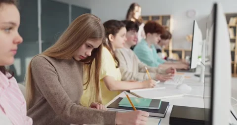Focused teen students in computer lab with teacher, studying and using desktops Stock Footage 332885460