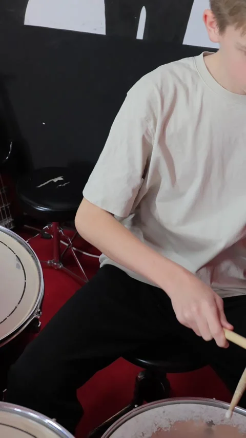 Focused teenage drummer practicing rhythms on drum kit in a modern music studio Stock Footage 322005609