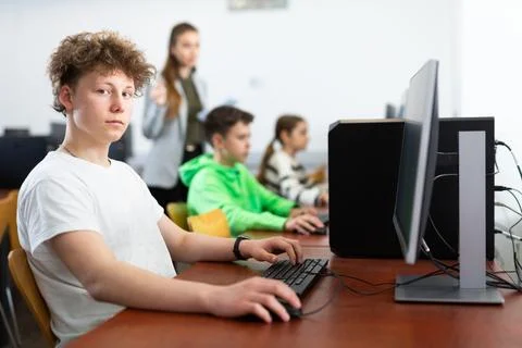 Focused teenager studying with classmates in computer lab Stock Photos