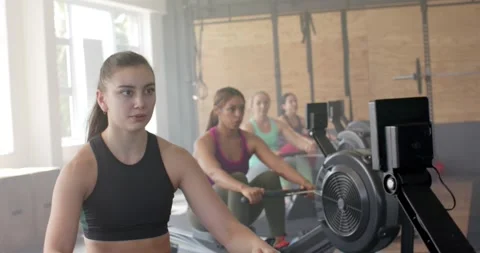 Focused unaltered diverse women exercising on rowing machines at gym, in slow Stock Footage 335866336