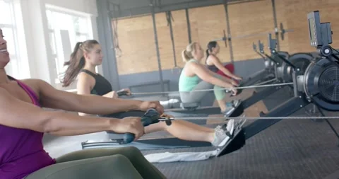Focused unaltered diverse women exercising on rowing machines at gym, in slow Stock Footage 340964044