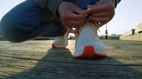 Focused Urban Routine: Man Tying Sneakers Before City Walk At Sunset Stock Footage 309475844