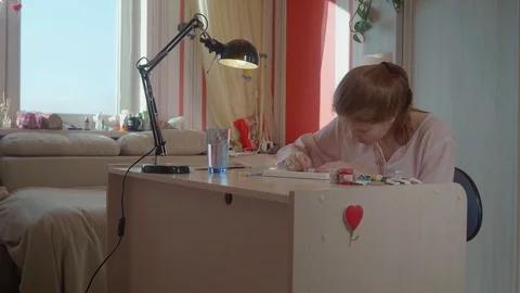 Focused view of girl drawing at table near window. Close up side view. Stock Footage 130121103