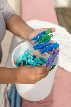 A focused view of hands selecting clothespins from a bucket, set in a home Stock Photos