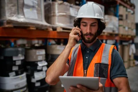 Focused warehouse manager tracking supply order details using digital tablet Stock Photos