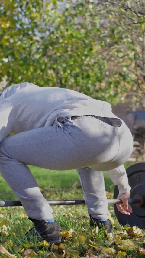 Focused Weightlifting in an Invigorating Autumn Park Setting for Enhanced Stock Footage 308743337