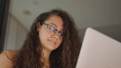 Focused woman examining computer interface under gentle lamp light. Close Stock Footage 330535459
