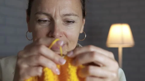 Focused woman knitting with yellow yarn at home Stock Footage 329057631
